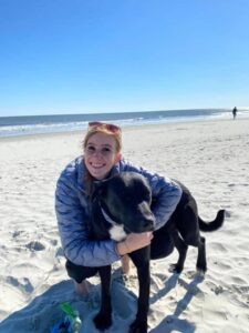 girl smiling on beach with dog